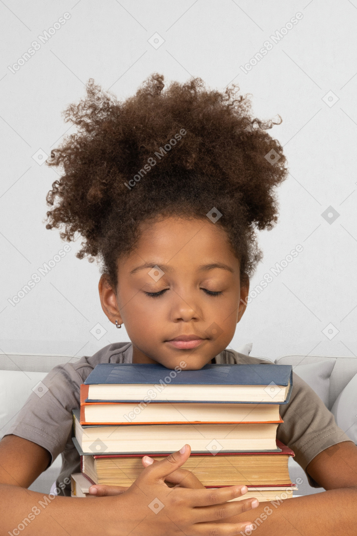 Menina, segurando um monte de livros com os olhos fechados