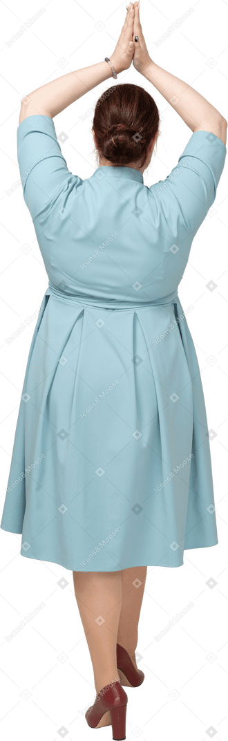 Вид сзади женщины в синем платье, делая молитвенный жест