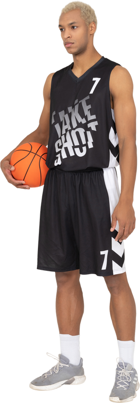 Vue de trois quarts d'un jeune joueur de basket-ball tenant un ballon