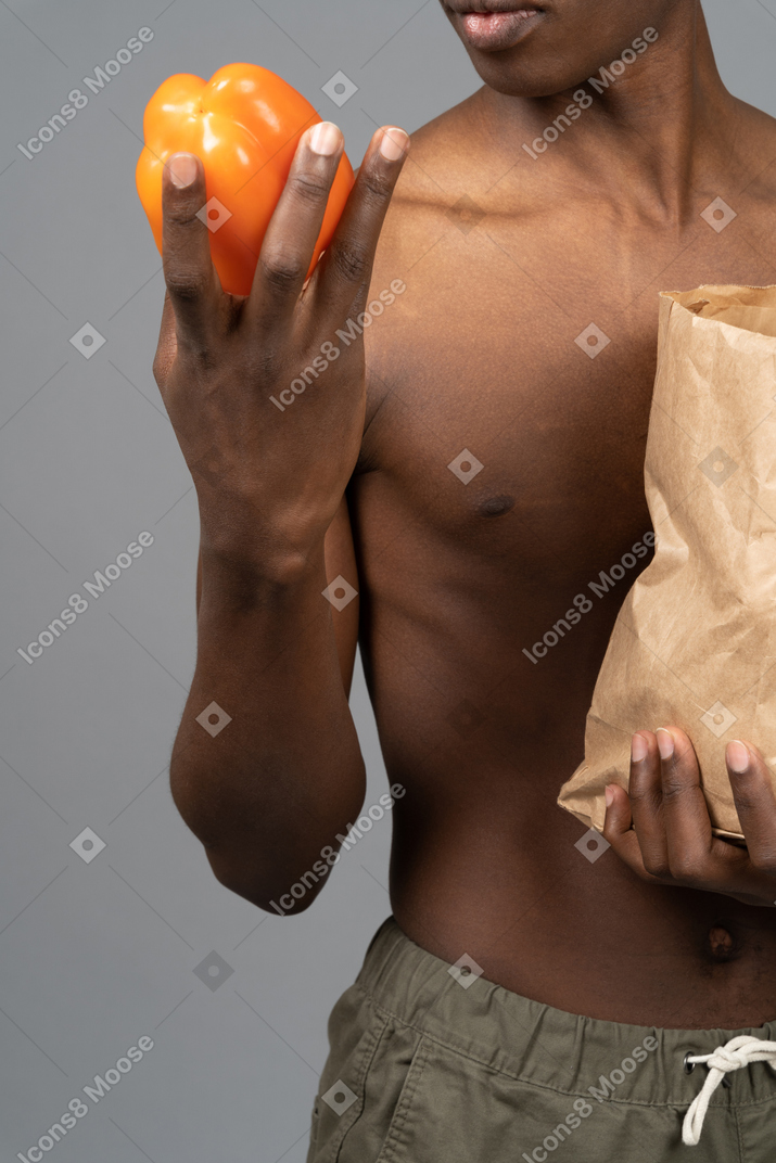 Um jovem segurando um pimentão na mão