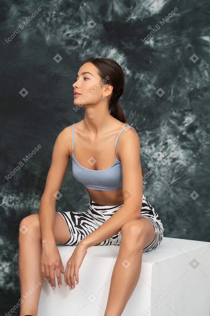 A portrait of a female athlete sitting confidently on a cube