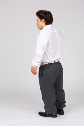 Вид сзади в три четверти на молодого человека в деловой повседневной одежде, стоящего с закрытыми глазами