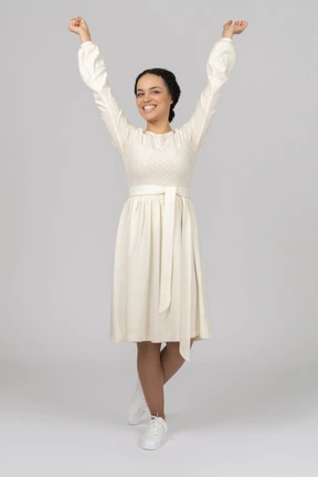 Excited young woman looking at camera with her hands in the air