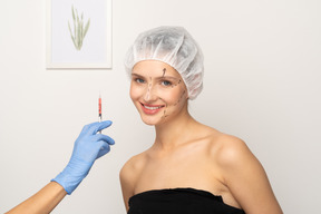 Young woman smiling and gloved hand holding up syringe