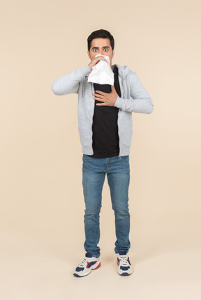 Young caucasian man breathing into a paper bag