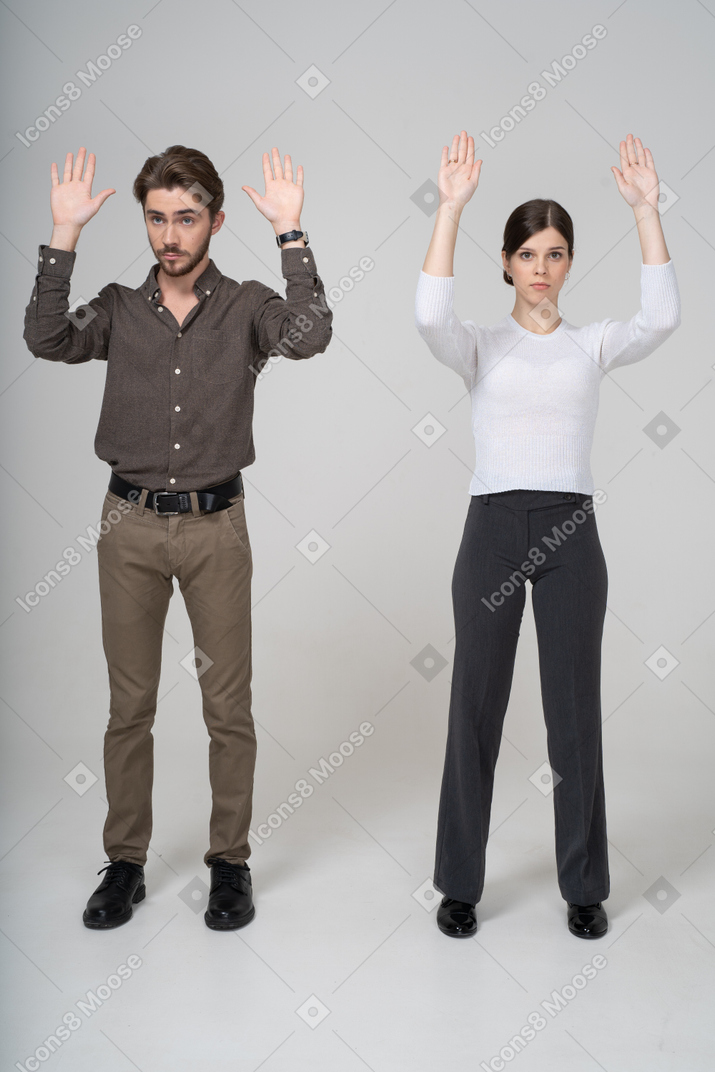 Молодая пара в офисной одежде, поднимая руки, вид спереди