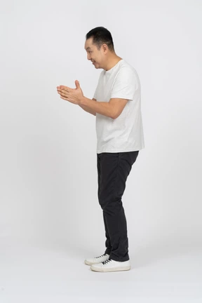 Side view of a cheerful man in casual clothes rubbing hands