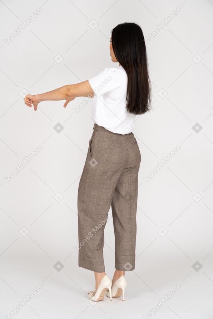 一位年轻的女士，穿着马裤和t恤，拇指朝下的四分之三后视图
