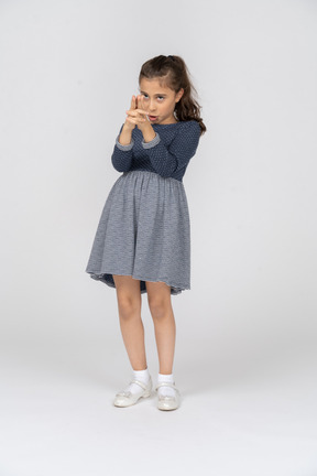 Vista frontal de una niña apuntando intensamente con una pistola de dedos