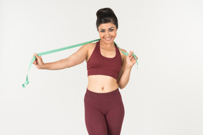 Young indian woman in sportswear holding cloth ruler