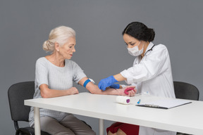 Doctora tomando sangre de la vena del paciente