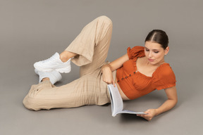 Young woman lying down with book