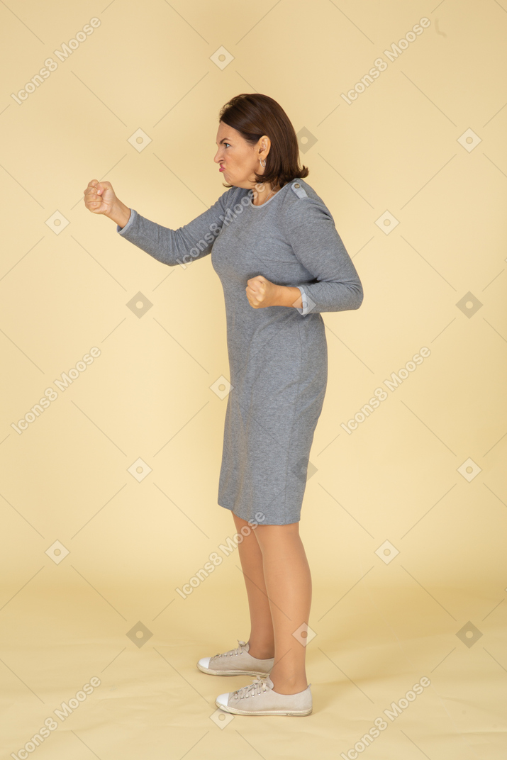 Vista laterale di una donna arrabbiata in abito grigio