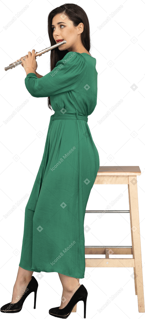 一位年轻的女士穿着绿色的衣服坐在椅子上，一边演奏单簧管的侧视图