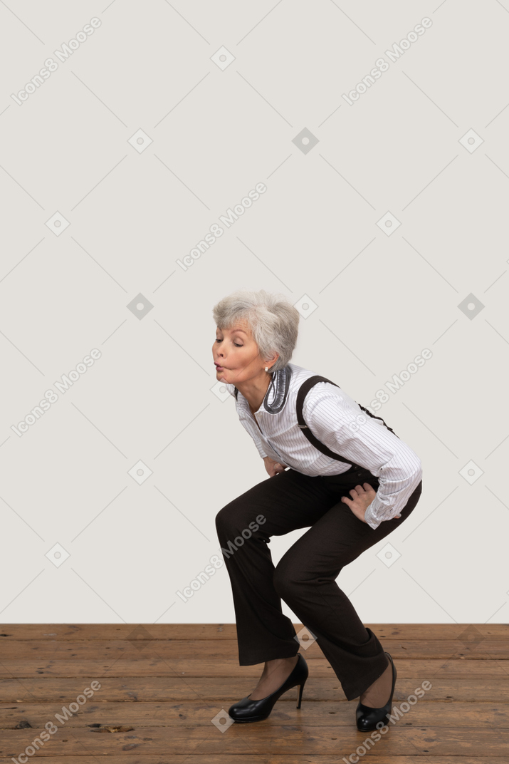 Трехчетвертный вид сидящей на корточках и свистящей старушки
