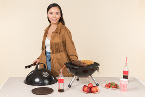 Jovem mulher asiática fazendo churrasco