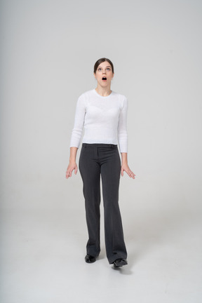 Front view of an impressed woman in white blouse and black pants