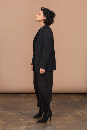 Side view of a businesswoman in a black suit throwing head back and pouting