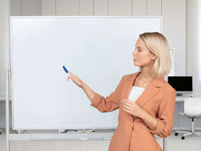 A woman is pointing at a whiteboard in an office
