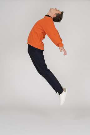 Junger mann im orange sweatshirt springen