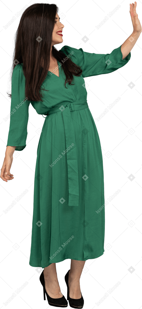 Vista de tres cuartos de un saludo señorita en vestido verde