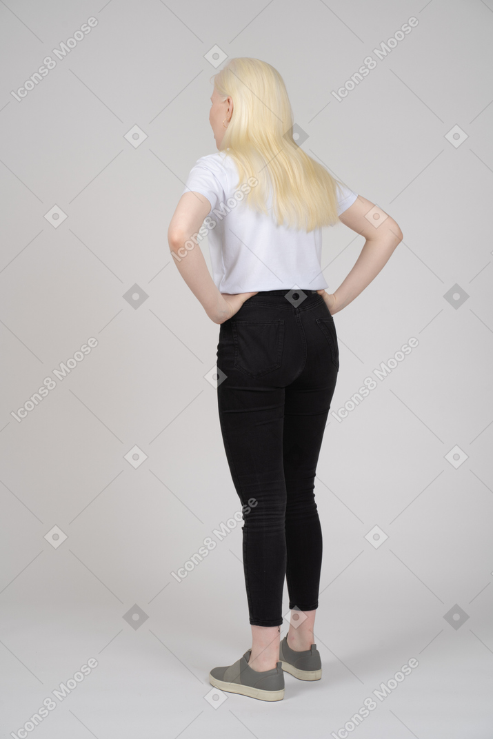 Back view of a standing girl with hands on her waist