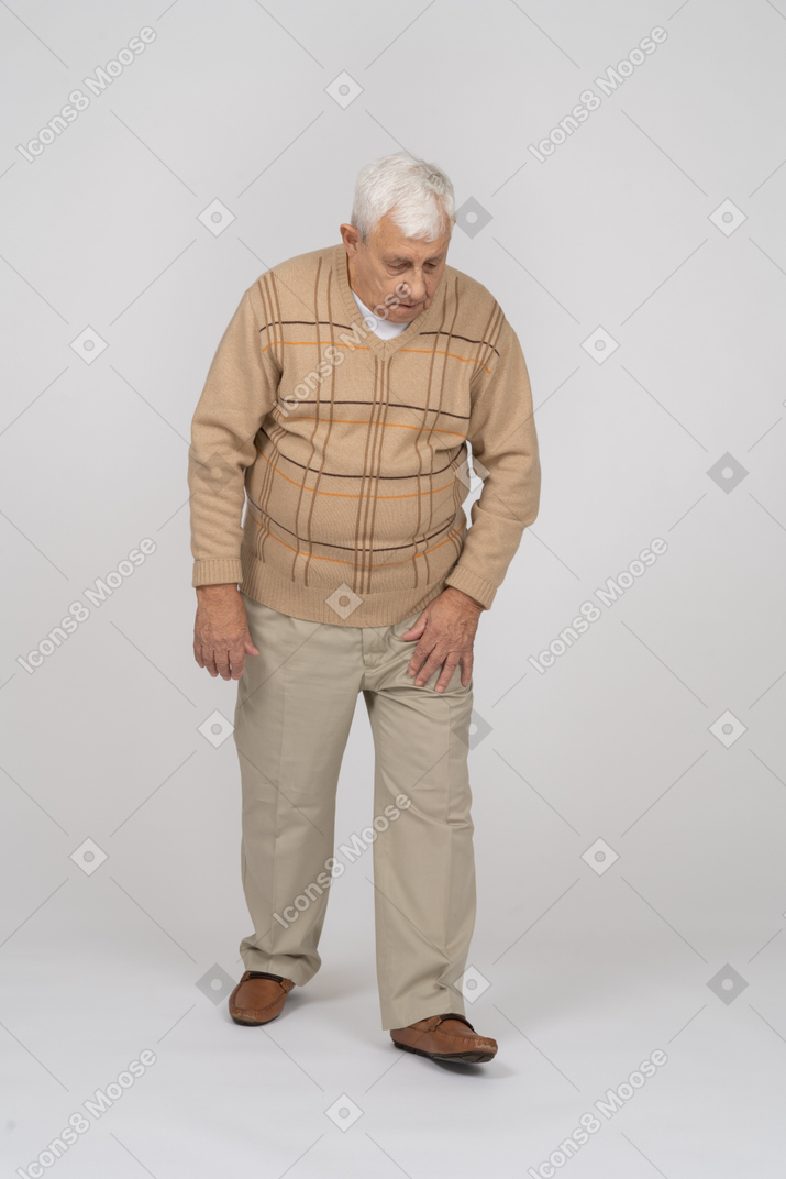 Вид спереди на старика в повседневной одежде, идущего вперед и смотрящего вниз