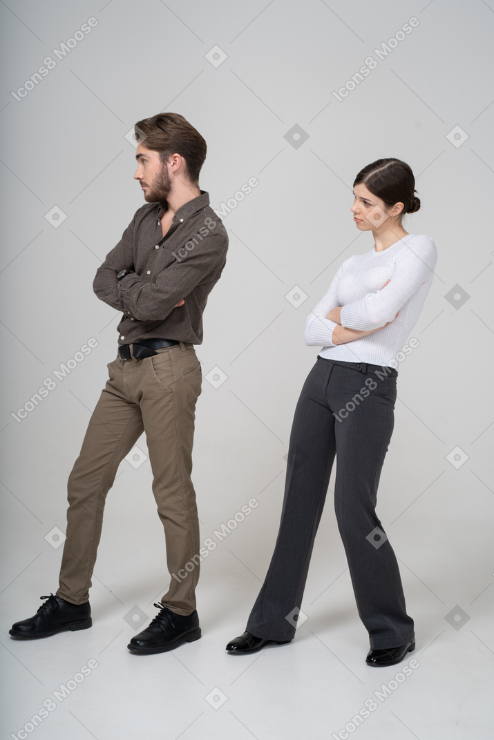 Vista de tres cuartos de una pareja joven en ropa de oficina cruzando los brazos