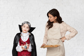 一个十几岁的男孩打扮成吸血鬼和一个年轻的女人抱着一些饼干