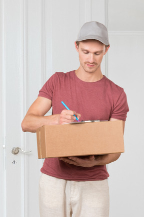 A man holding a cardboard box and a pen