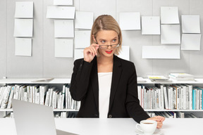 Business woman lowering her eyeglasses and looking aside