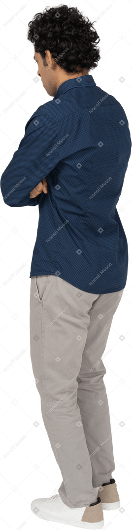 Vue latérale d'un homme en vêtements décontractés debout avec les bras croisés