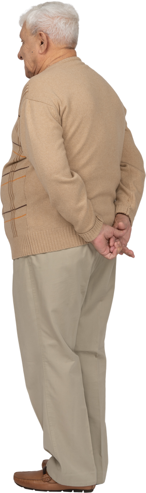 一位身穿休闲服、双手背在身后站立的老人的后视图