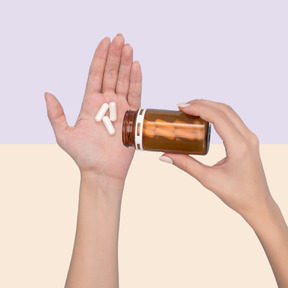 A hand with pills and a pill bottle