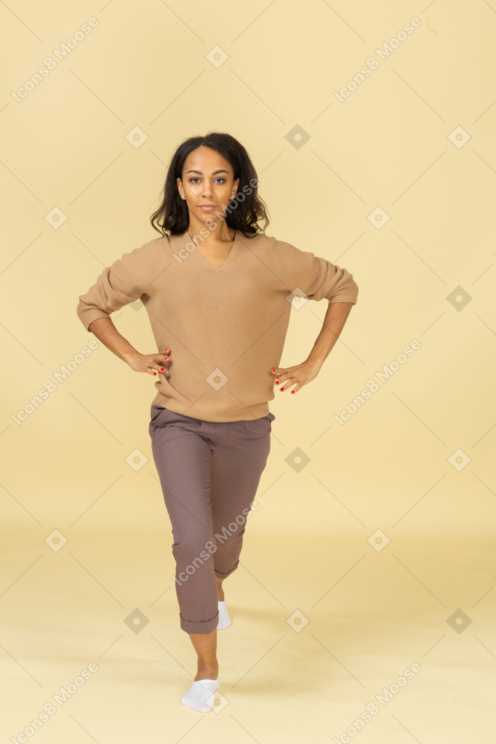 Вид спереди сидящей на корточках темнокожей молодой женщины, делающей выпад