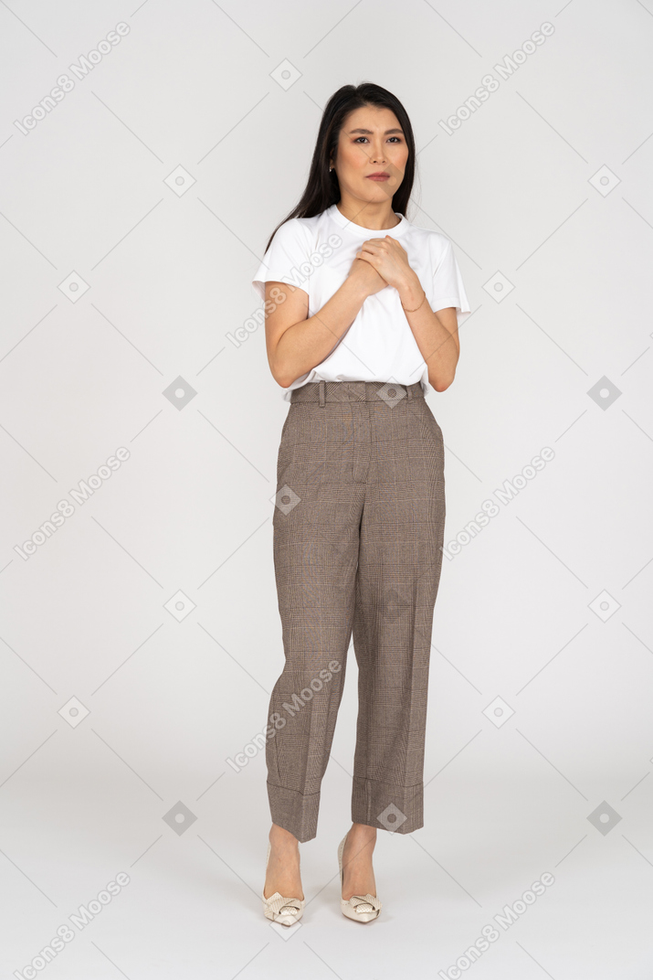 Front view of a sad young lady in breeches and t-shirt touching chest