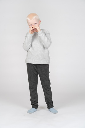 Front view of a boy covering his mouth with hands