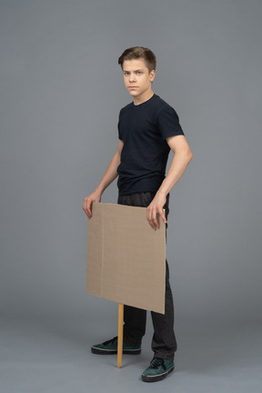 Serious young man standing with a blank  poster