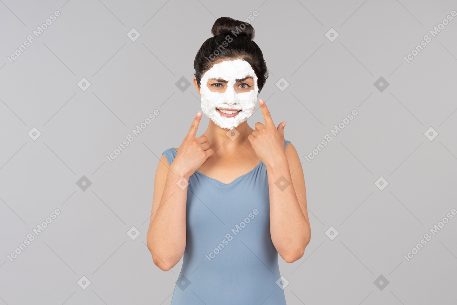 Woman with white facial mask on pointing at her face