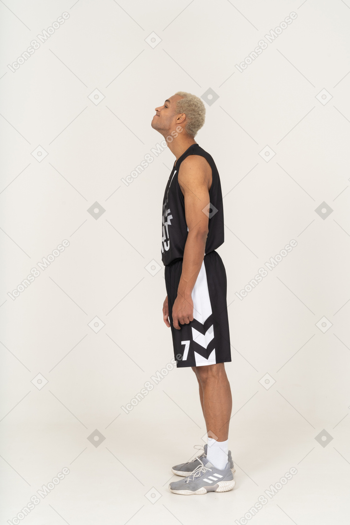 Vista lateral de um jovem jogador de basquete levantando a cabeça
