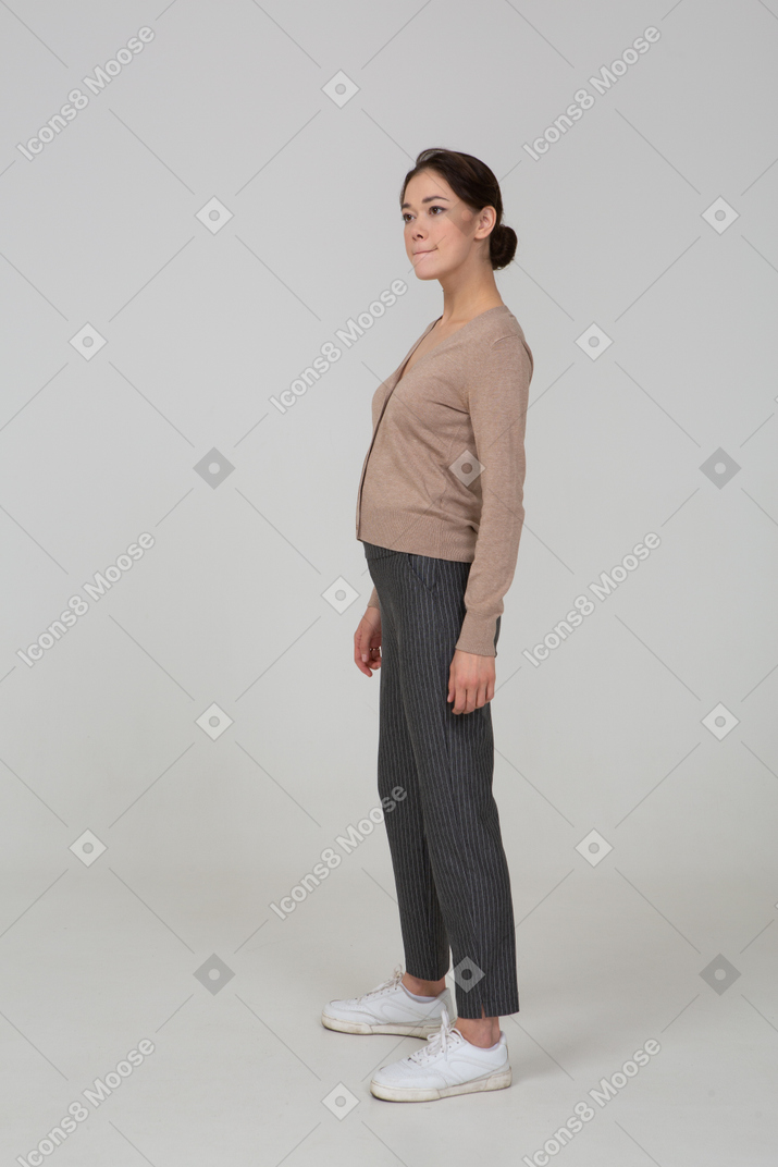 Three-quarter view of a displeased female in pullover and pants pressing lips