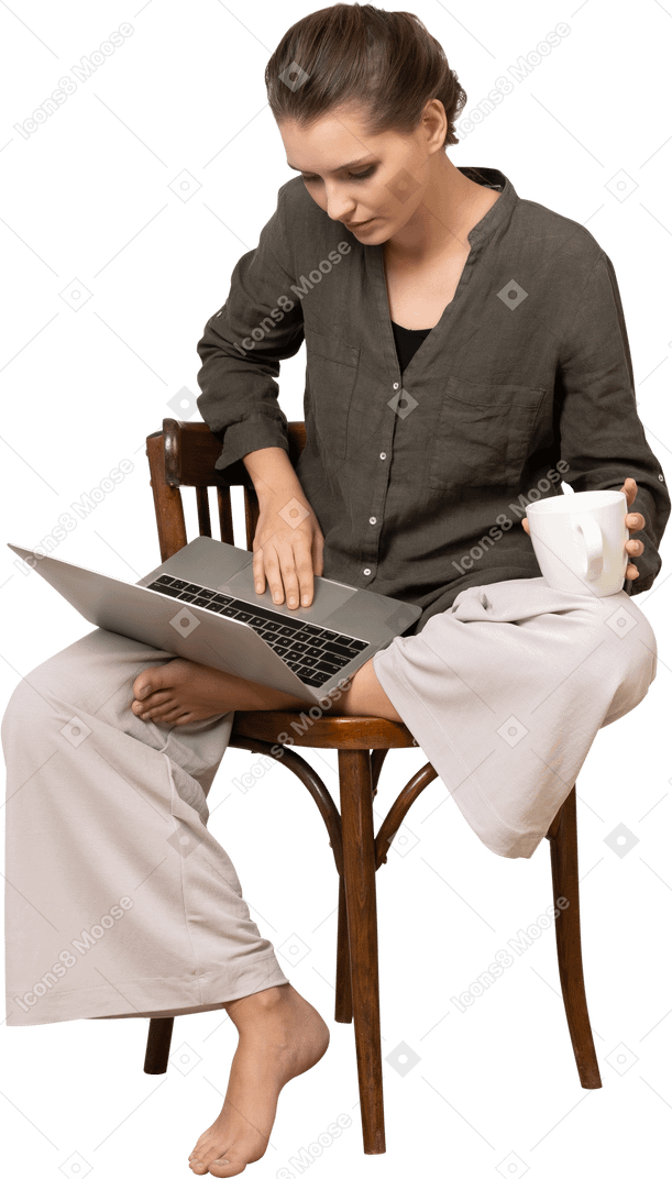 노트북과 커피 컵이 있는 의자에 앉아 있는 젊은 여성의 전면 모습
