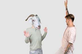 A man standing next to a man with a goat head on his head