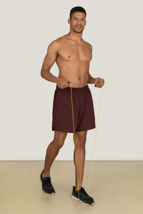 Bare chested young man in sport shorts standing on the jumping rope