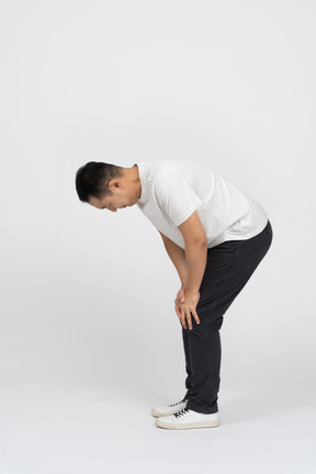 Side view of a man bending down and touching hurting knee