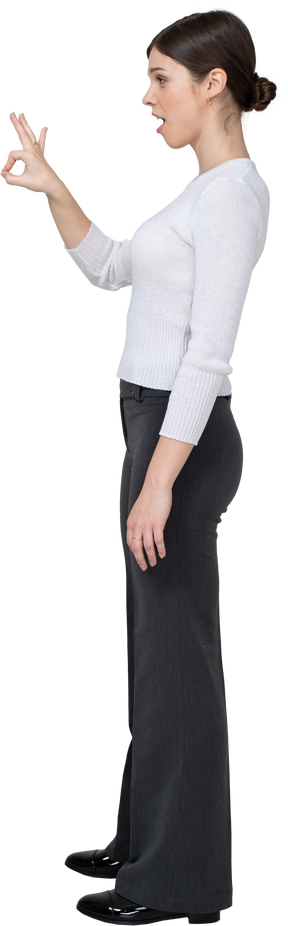 Side view of a young woman in office clothing showing ok sign