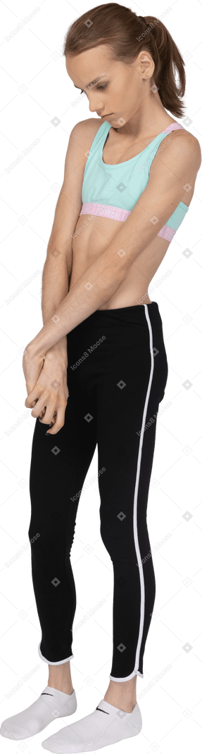 Vue latérale d'une adolescente timide en tenue de sport, main dans la main