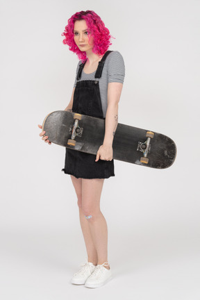 Hunchbacked teenage girl holding a skateboard in profile