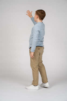 Young boy in blue shirt and khaki pants reaching up