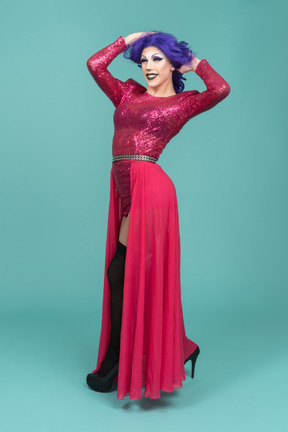 Portrait of a drag queen in pink dress smiling while messing up hair